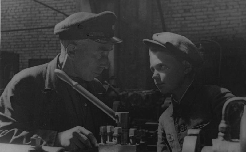 Бригадир цеха завода «Большевик» и его 15-летний ученик у токарного станка. Июнь 1943 г. 