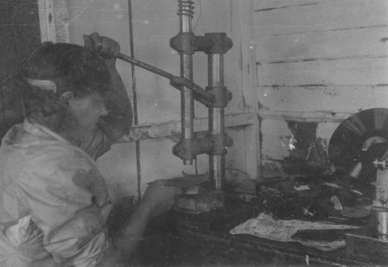 Работница Новотрубного завода Первоуральска штампует пуговицы из старых грампластинок. 1943 г. 