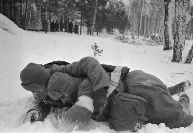 Санинструктор по снегу выносит раненого красноармейца. Постановочное фото. 1941 г. 