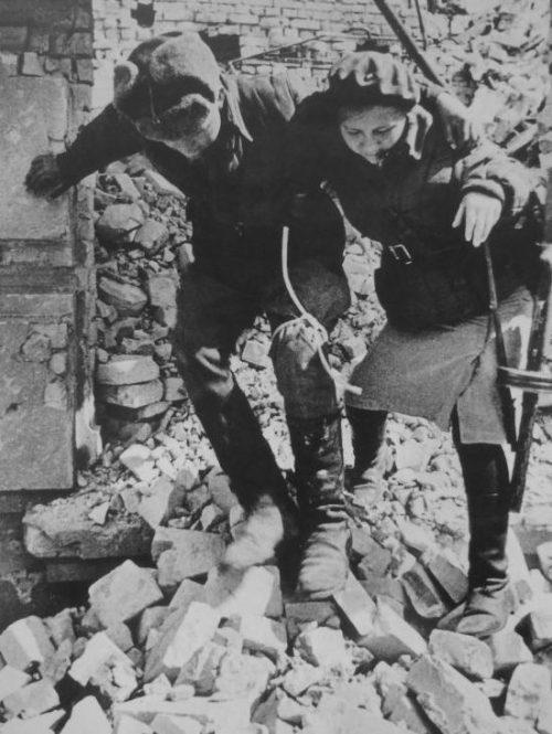 Девушка-санинструктор сопровождает раненого солдата в Сталинграде. Октябрь 1942 г.