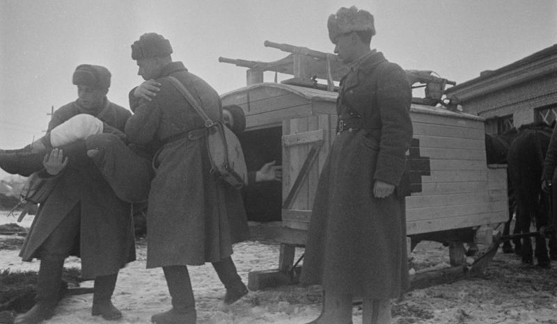 Санитары выгружают раненого красноармейца из санитарных саней. 1942 г. 