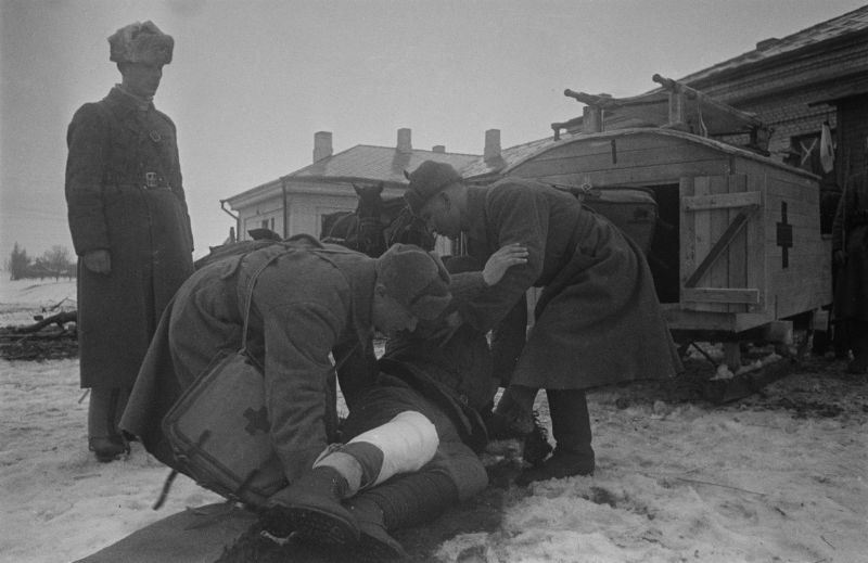 Санитары выгружают раненого красноармейца из санитарных саней. 1942 г. 