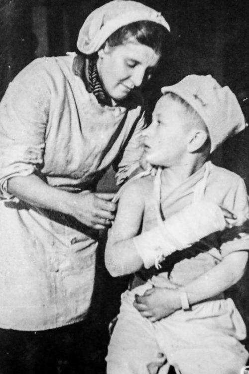 Медсестра делает перевязку раненому ребенку в госпитале блокадного Ленинграда. Декабрь 1943 г.
