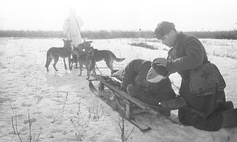 Санинструктор перевязывает голову раненого бойца перед отправкой его в тыловой госпиталь. 1943 г. 