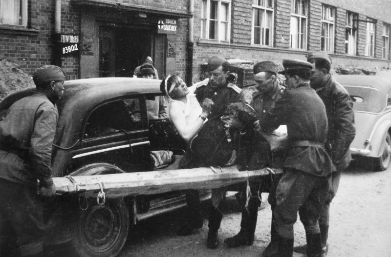 Санитары укладывают доставленного раненого на носилки. Германия, май 1945 г.