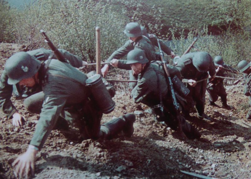 Немецкие солдаты поднимаются по склону холма над рекой в Бельгии.1940 г.