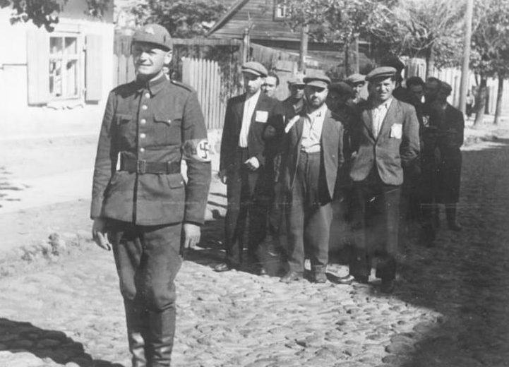 Литовский полицай сопровождает группу литовских евреев в Вильнюсе. Июль 1941 г.