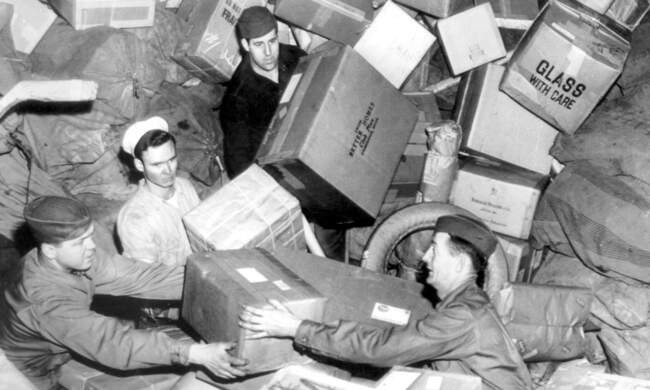 Американские военнослужащие под грудами посылок в армейском почтовом отделении.