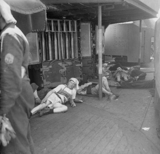 Расчет 4-дюймового орудия отдыхает на борту HMS Manchester во время затишья в боях.