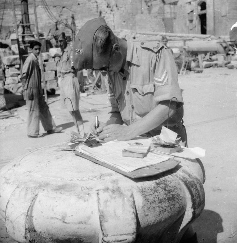 Разгрузка припасов на Мальте: капрал проверяет припасы на причале. Август 1942 г.